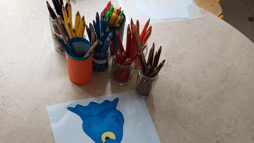 Färgglada pennor och en ritning på ett bord på en förskola.