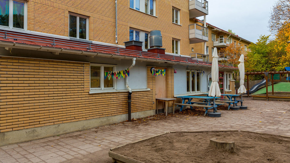 Gul byggnad med uteplats och sandlåda, foto.