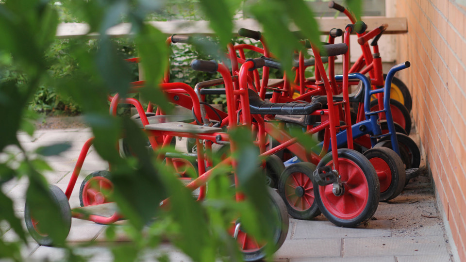 Röda cyklar framför en tegelvägg. Framför cyklarna skymtas gröna växer.