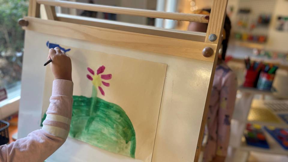 Två barn målar på staffli.