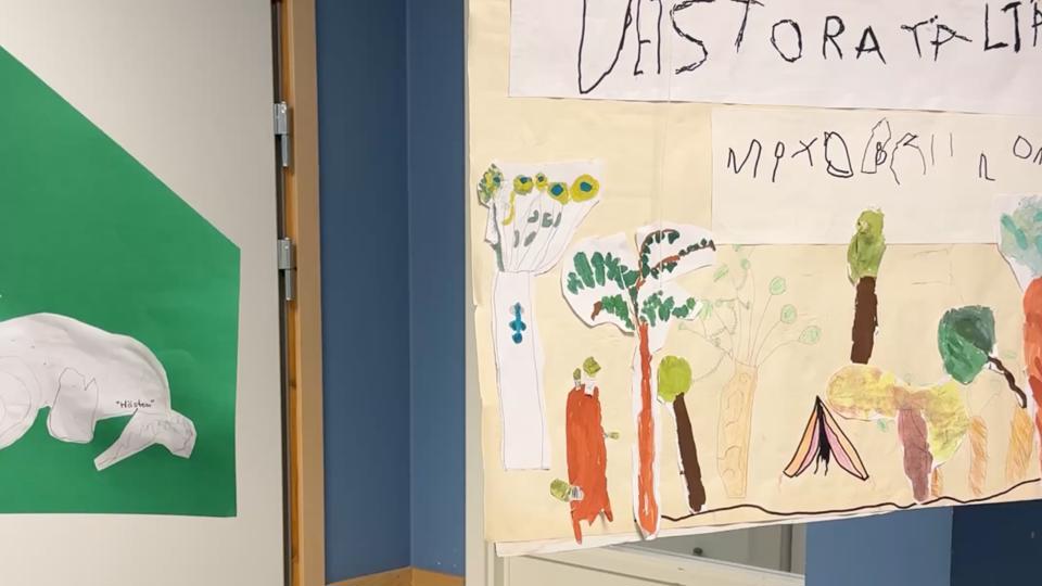 Målning på dörr med träd, tält och solrosor, skapad av barn.