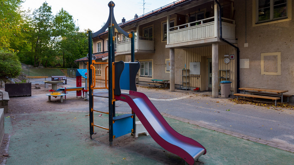 Rutschkana och klätterredskap utanför förskolebyggnad.