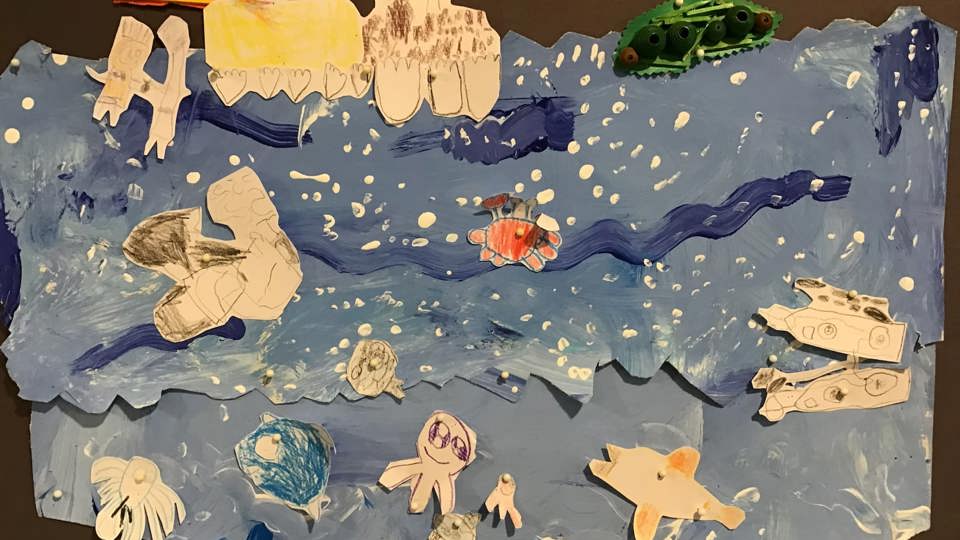 Barnteckningar av havsdjur och en båt, fästa på blå bakgrund som föreställer havet.