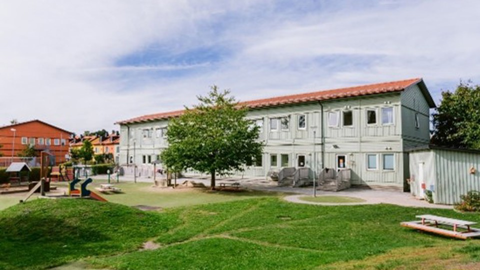 Grön förskolebyggnad på grästomt