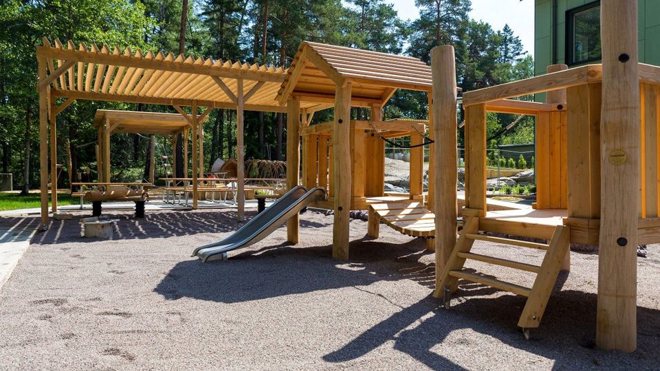 Gård med sittplatser och lekobjekt där man kan klättra och åka rutschkana.