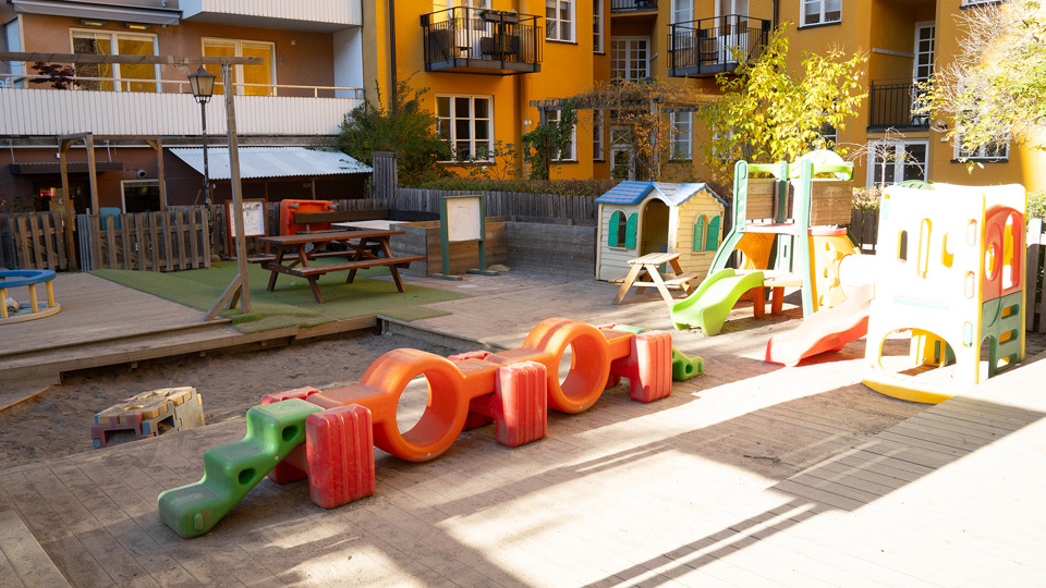 Innergård med lekyta för mindre barn med klätterhus och sandlåda.