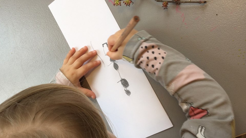 Barn som ritar av en kvist.