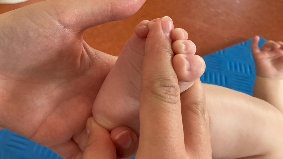 Hand som håller i en bebisfot.