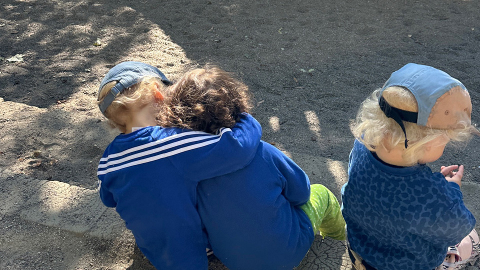 Barn som sitter vid en sandlåda.