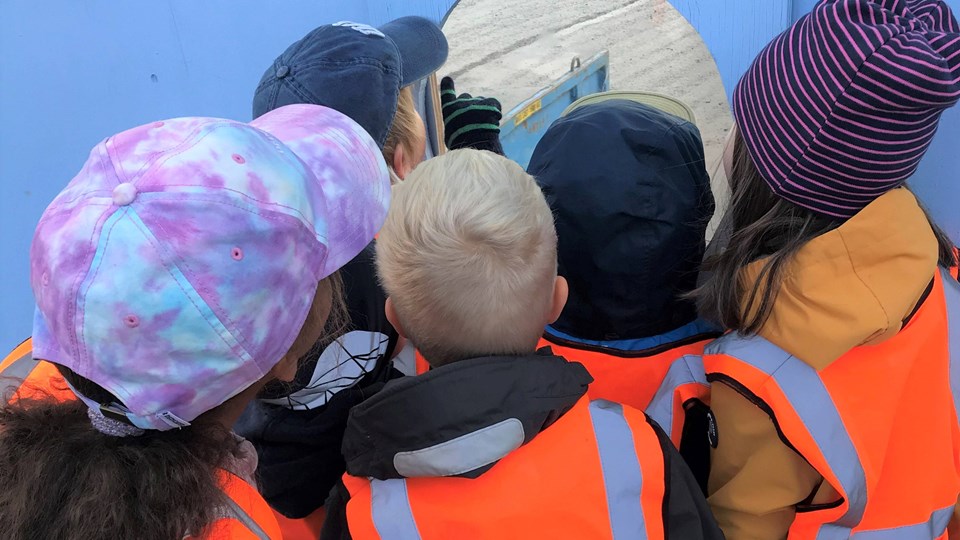 Barn kikar på Slussenbygget genom hål i plank.