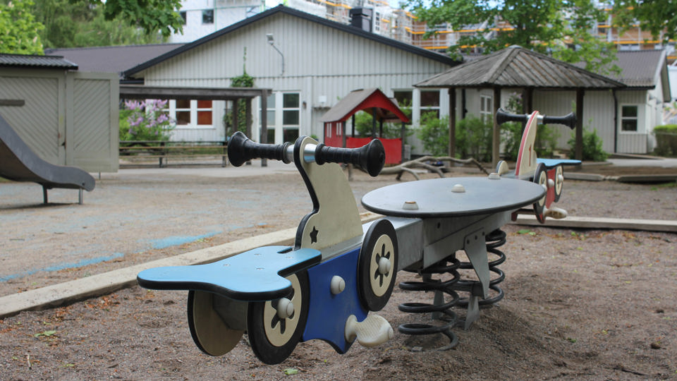 Blå bilgunga på stor utegård framför Mumindalens förskola.