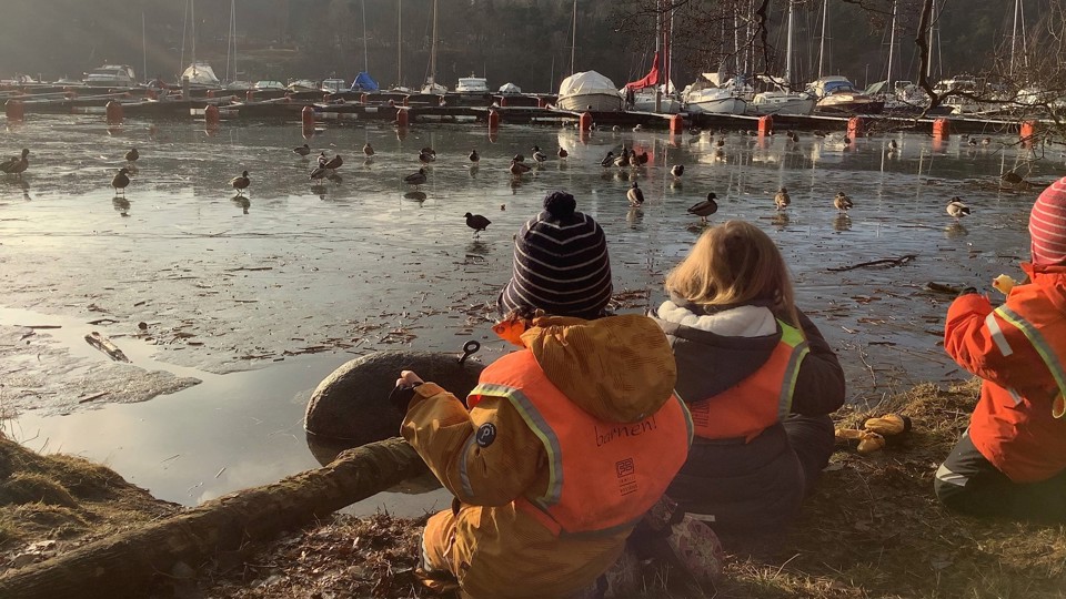 Barn sitter vid vattnet.