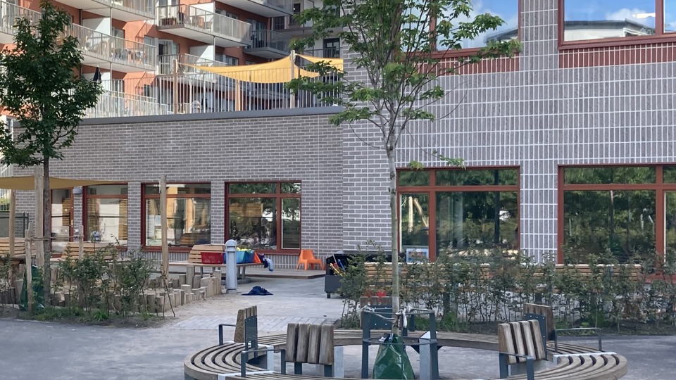 Gården med sittgrupp och lekredskap, förskolan i bakgrunden.