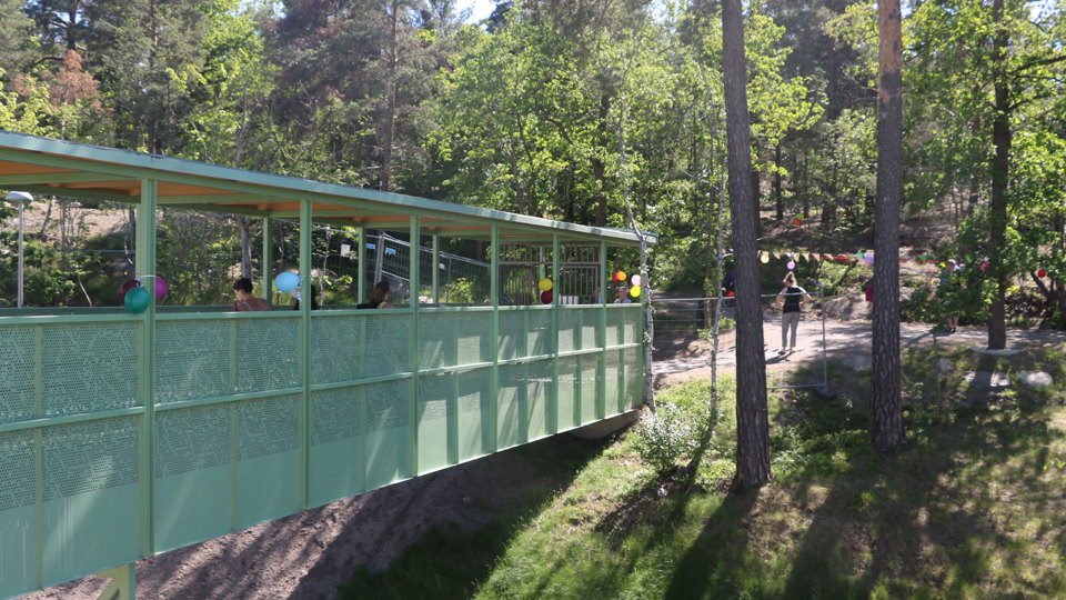 Spång från förskolan till naturmark med träd.