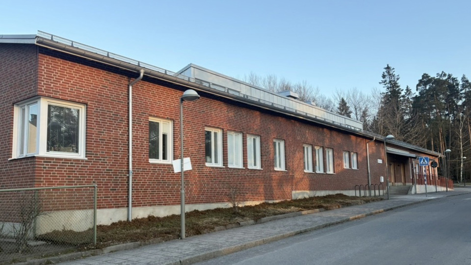 Tegelbyggnad med skog i bakgrunden.