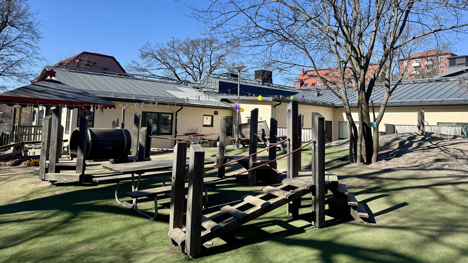 Solbelyst gård utanför förskola. Träredskap i förgrund, foto.