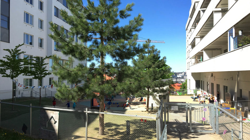 Utemiljö med lekytor, grönska och mellan vita flerbostadshus.