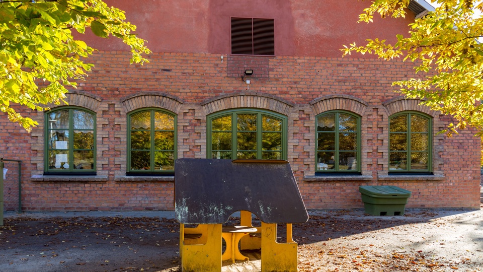 Byggnad med träd och lekobjekt utanför