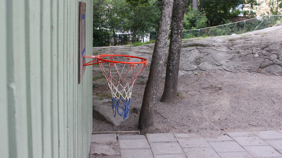 En basketkorg hänger på en grönmålad trävägg.