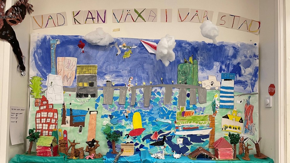 Förskolebarn målat, klippt och klistrat djur, människor, hav och byggnader på en stor yta. 