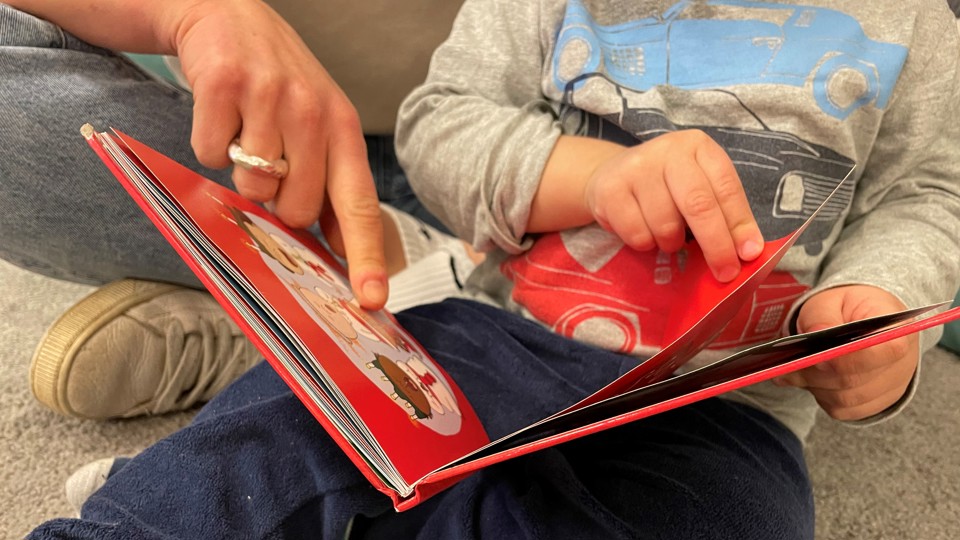 Barn och pedagog bläddrar i bok.