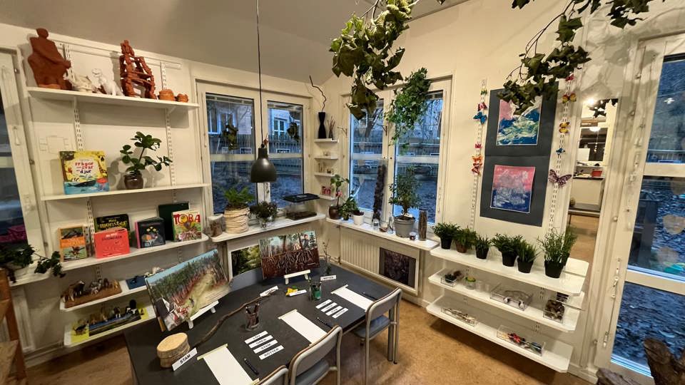 Målarbord med en gul pumpa i mitten, penslar, färgkoppar och papper för barnens målande.