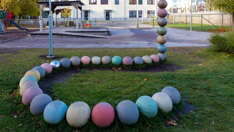 Gård med lekhus, sandlåda, klätterställning med mera samt hus i bakgrunden.