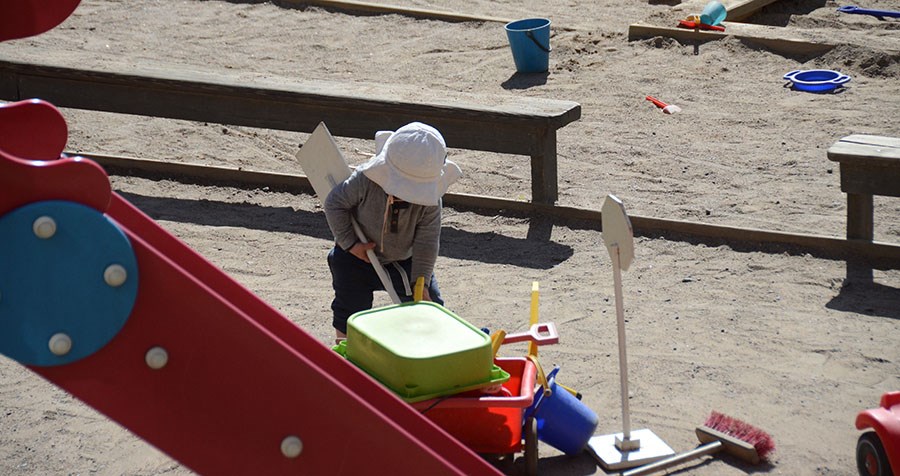 Barn leker i sandlådan med leksaker på förskolans utegård.