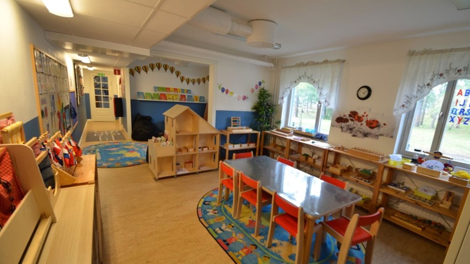 Inne i förskolan med bord, stolar och leksaker.