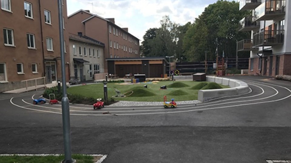 Förskolegården med bilbanor och en grön oas mellan husen på Bjulevägen.