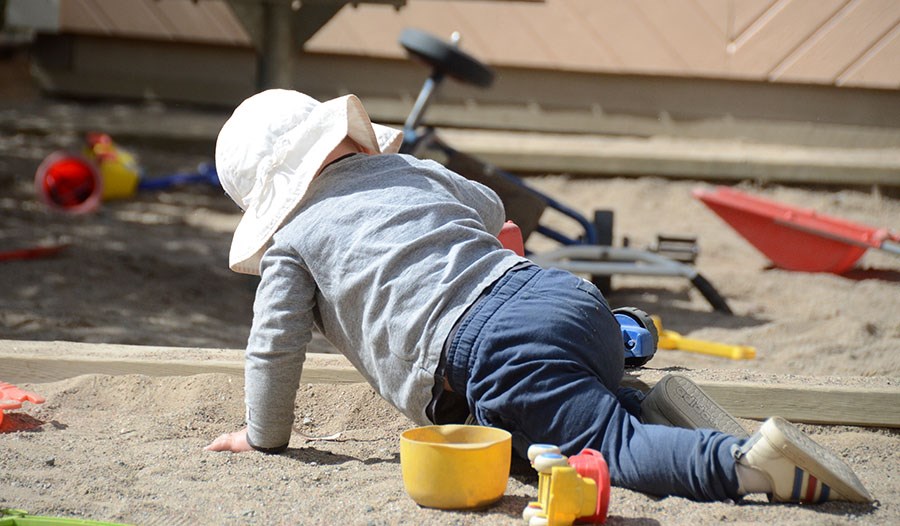 Ett barn leker i sandlådan på förskolans utegård.