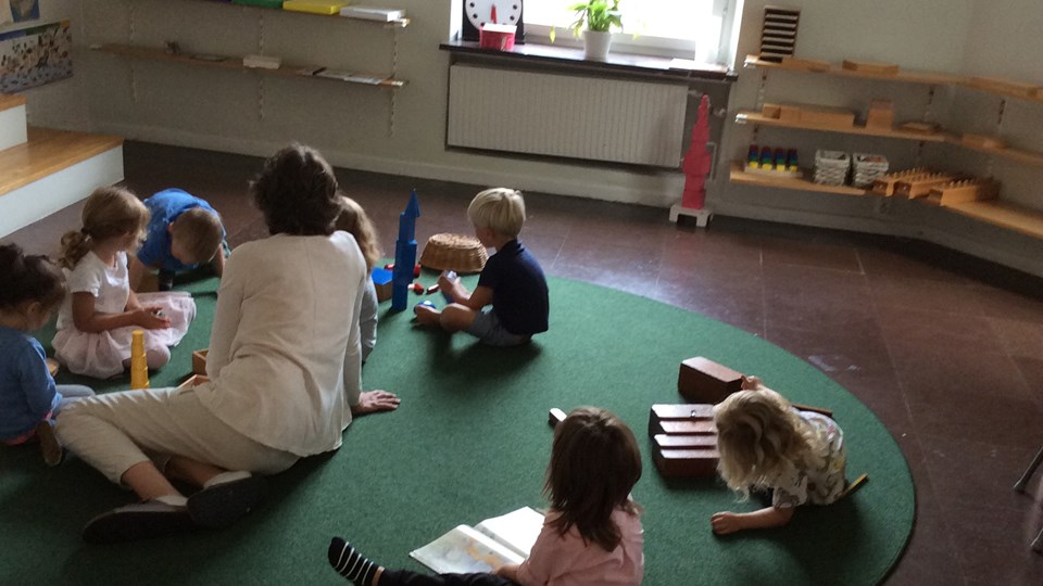 Barnen på förskolan sitter samlade på en matta tillsammans med pedagogen