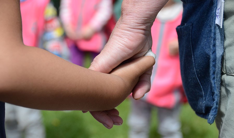 Barn och vuxen håller varandra i händerna.