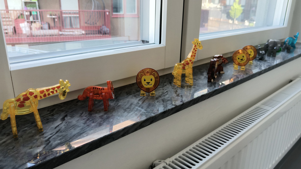 Små genomskinliga leksaksdjur uppställda på en fönsterbräda i en ljus förskolemiljö.
