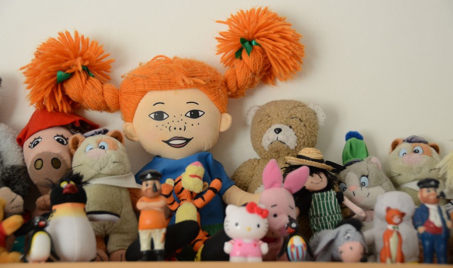 En samling leksaker och gosedjur på en hylla inne på förskolan.