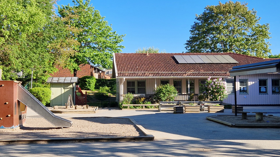 Förskolan Sylvester syns på förskolans innergård. Innergården har platser för lek, en rutschkana och en sandlåda.