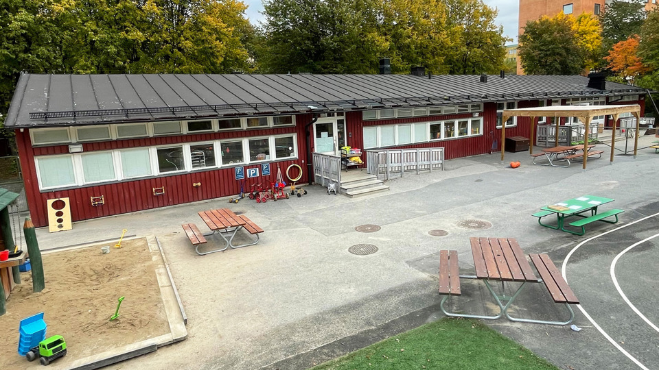 Utegård med klätterställning framför förskola. Bakom syns höghus.