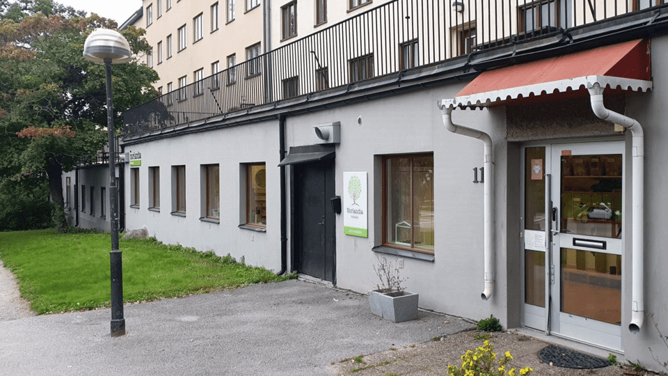 Förskolebyggnad med skylt där det står "Norlandia", entré och fönster mot gatan.