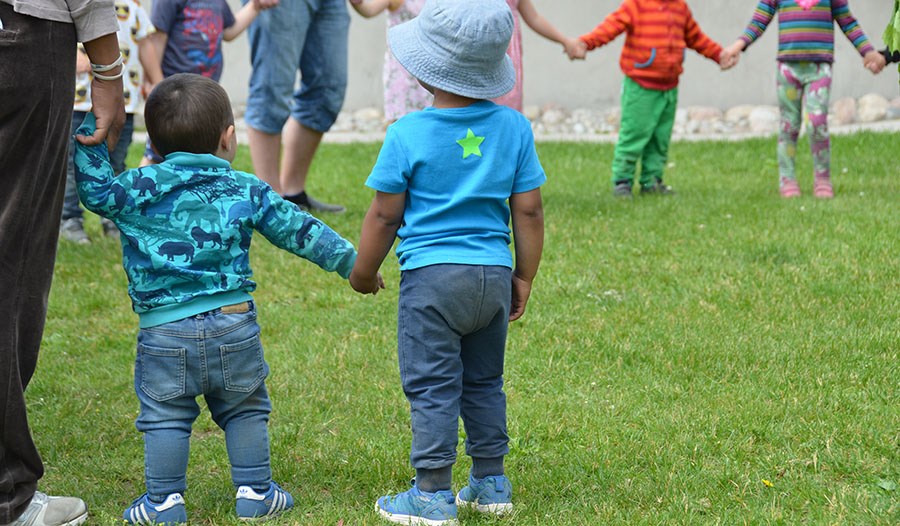 Barn håller händerna i en cirkel på gräsmatta.