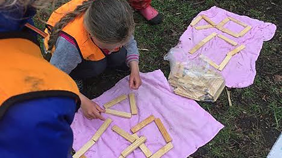 Barn formar mönster på marken med träbitar.