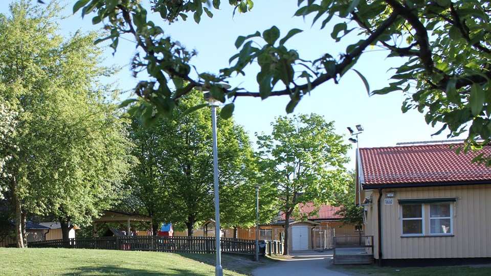 Förskolan Gläntan syns med sina gula fasader med en lummig gård och litet staket.