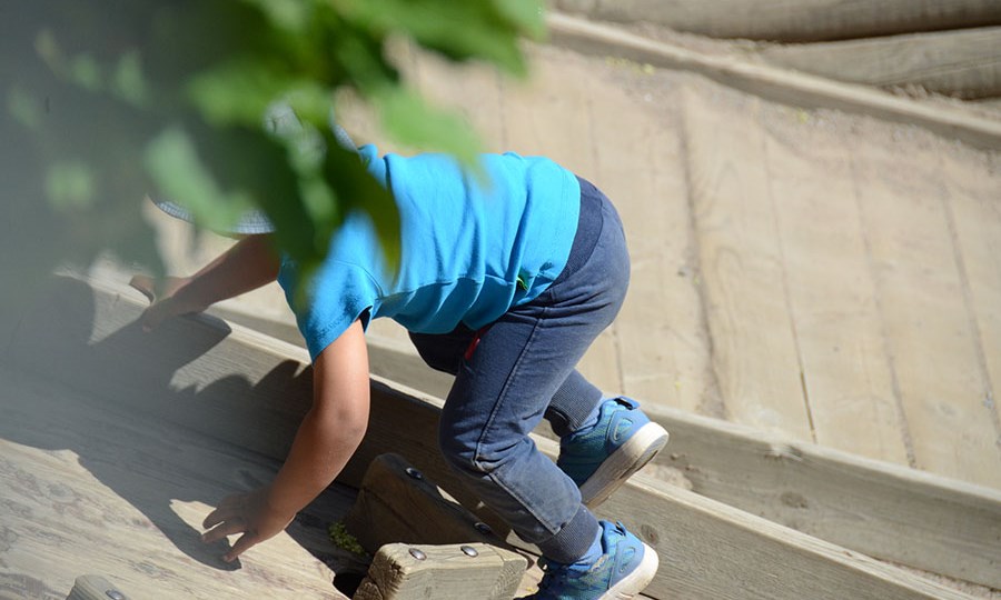Ett barn klättrar på klättervägg utomhus på förskolan.