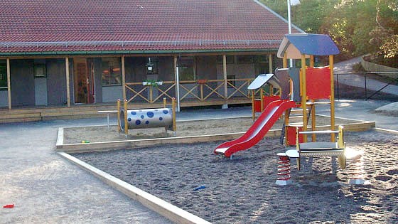 En bild på förskolan och en klätterställning och ruschkana i förgrunden